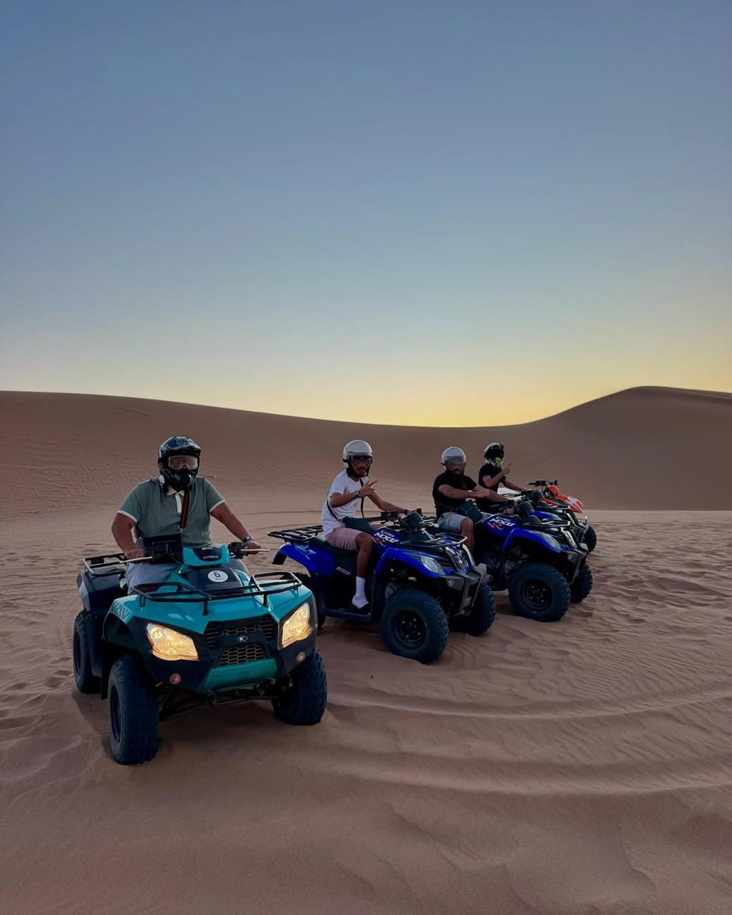 Four people on four blue quad bikes.